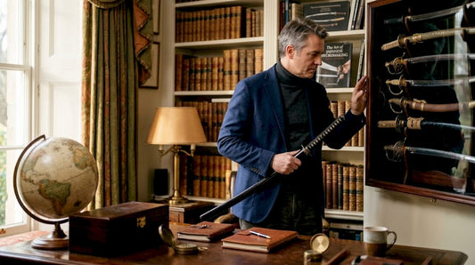 Collector examining a sword in home study